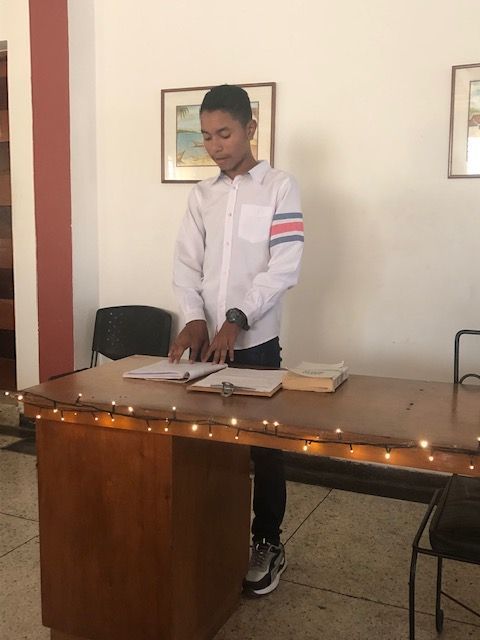 A man in a white shirt is standing at a desk