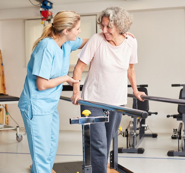 Woman using parallel bars in therapy gym