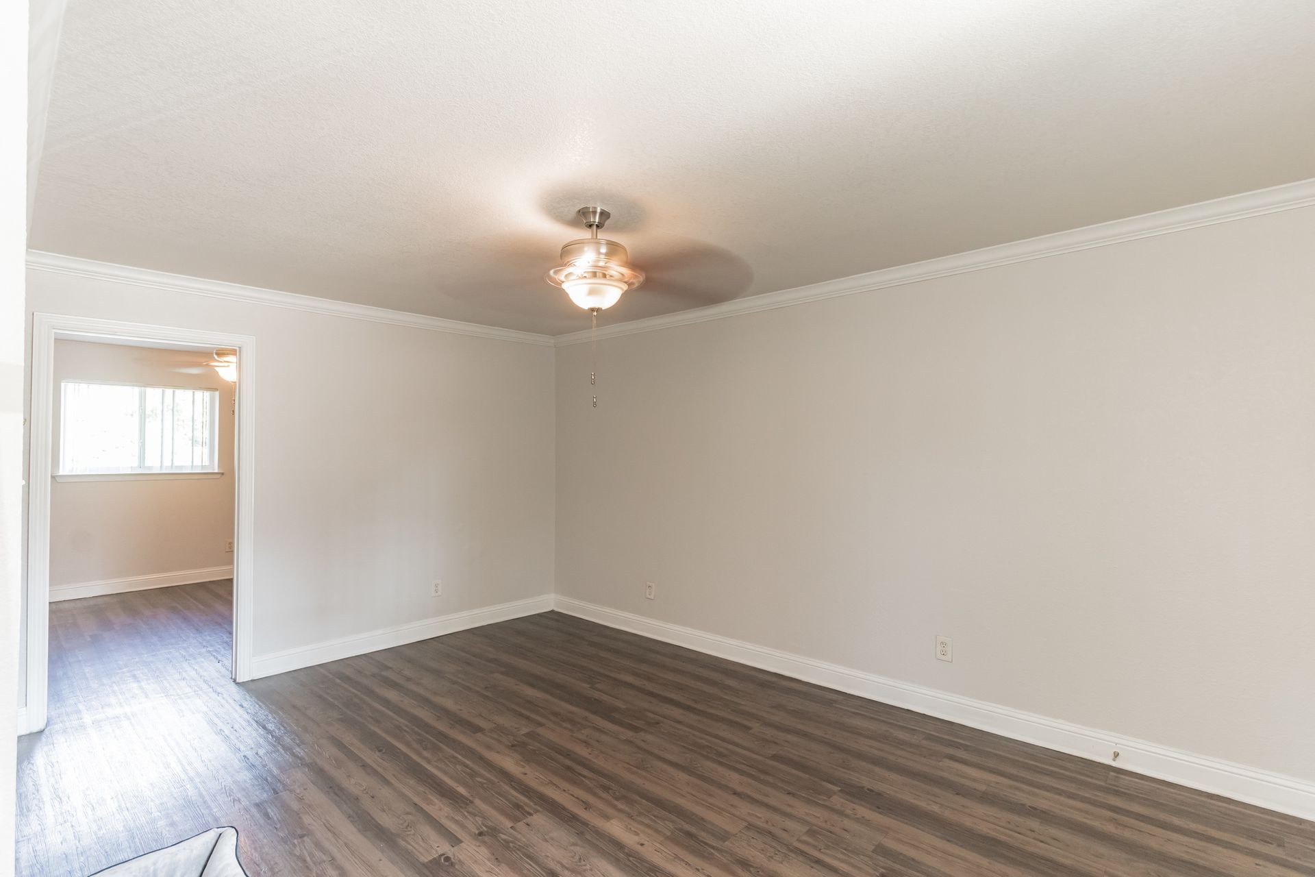 Photo of a large room with a ceiling fan and a door in the background, leading to a separate room