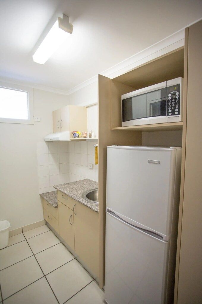 Two Twin Beds in a Room With Dark Blue Bedding, Small Window, and Ceiling Fan — Fourth Avenue Motor Inn in Parkside, QLD