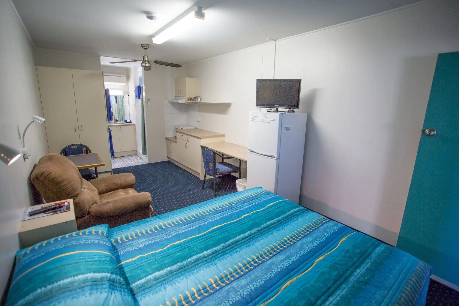 Hotel Room With Bed, Table, Cabinets, Refrigerator, and Partial Kitchen Area — Fourth Avenue Motor Inn in Parkside, QLD