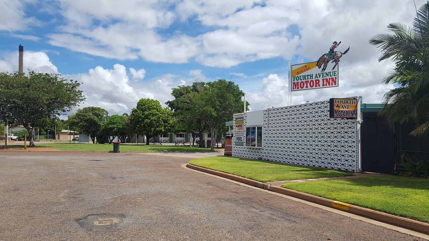 A Street Scene With a Cowboy-themed Sign, Trees, and a Cloudy Sky — Fourth Avenue Motor Inn in Parkside, QLD