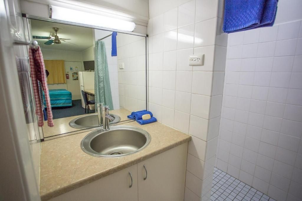 Bathroom With Sink, Mirror, and Shower. White Tiles, Blue Towel, Beige Countertop — Fourth Avenue Motor Inn in Parkside, QLD