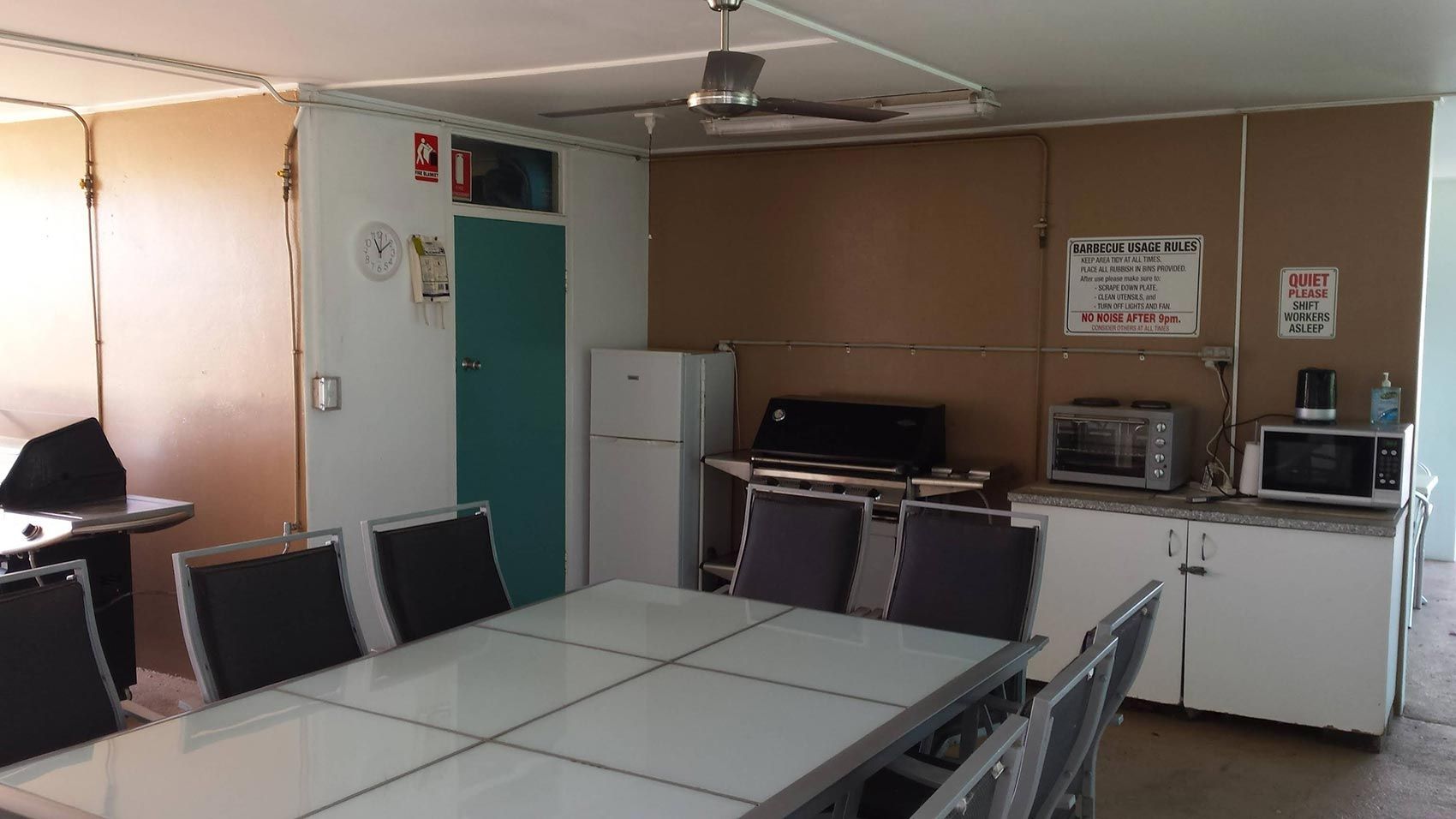 Dining Room With a Large Table, Chairs, and a Kitchen Area With Appliances — Fourth Avenue Motor Inn in Parkside, QLD