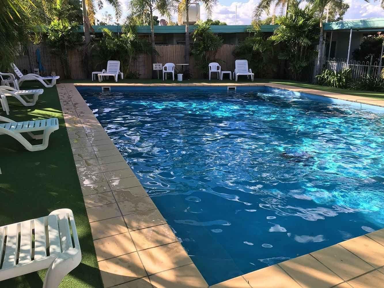 Swimming Pool Surrounded by a Concrete Border and Lounge Chairs — Fourth Avenue Motor Inn in Parkside, QLD