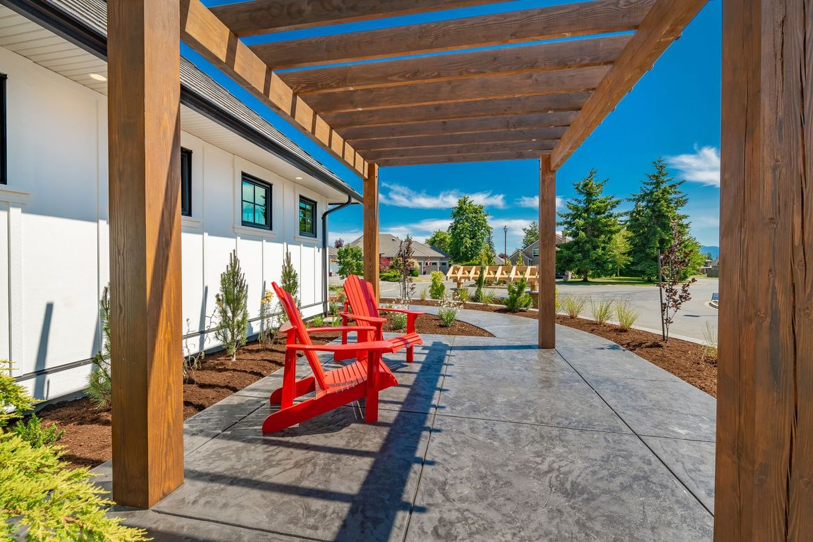 A row of red chairs are sitting under a wooden pergola.