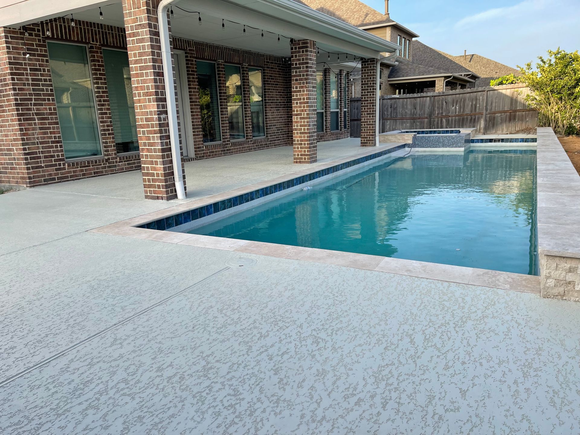 There is a large swimming pool in the backyard of a house.