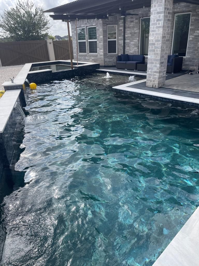 There is a large swimming pool in the backyard of a house.