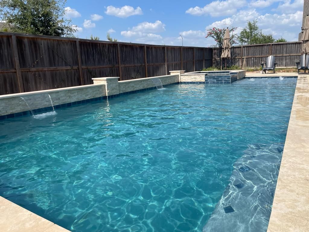 A large swimming pool with a wooden fence in the background.