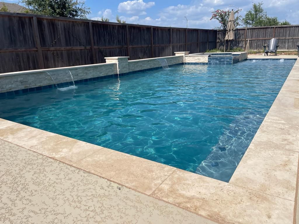 A large swimming pool with a wooden fence in the background.