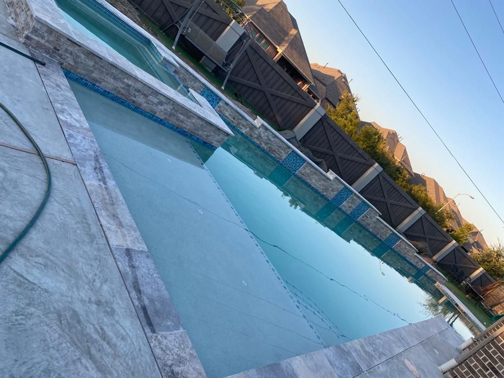 A large swimming pool is surrounded by a fence and a hose.