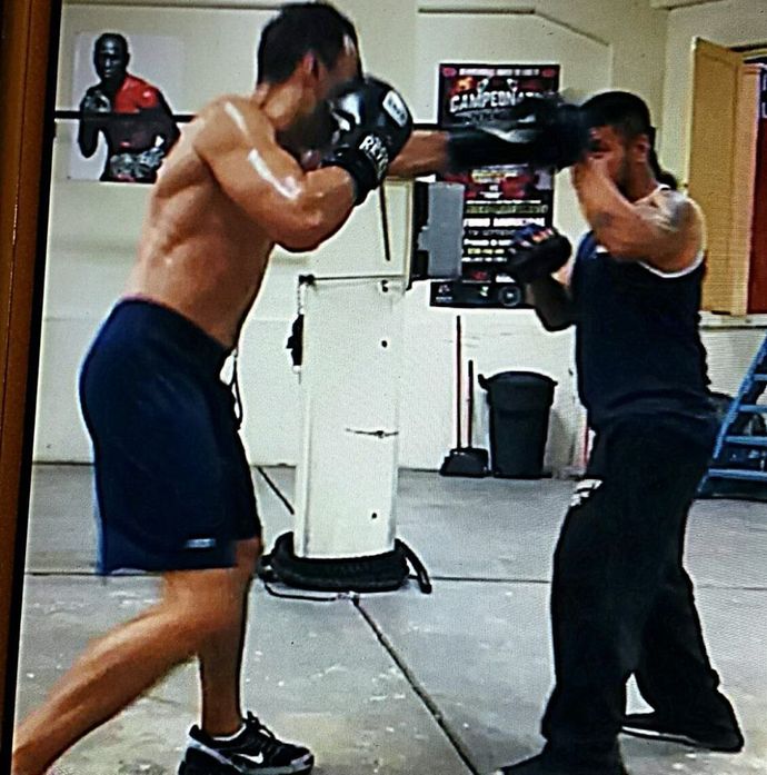 Two men are boxing in a gym with a poster on the wall that says campeon