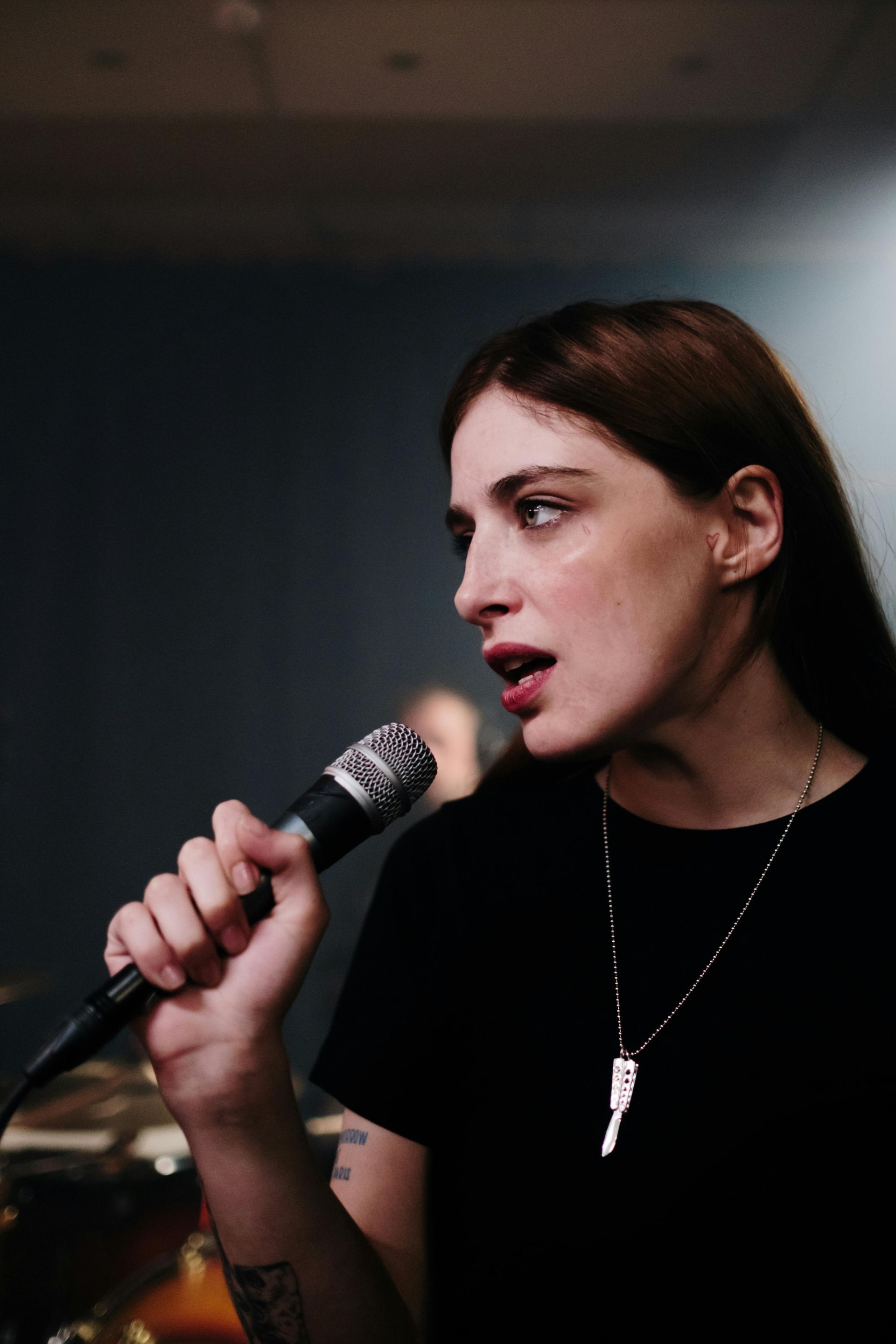 A woman is singing into a microphone in a dark room.