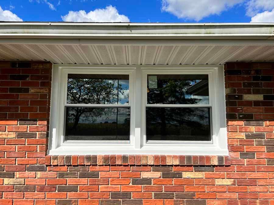 A brick house with a white window on the side of it.