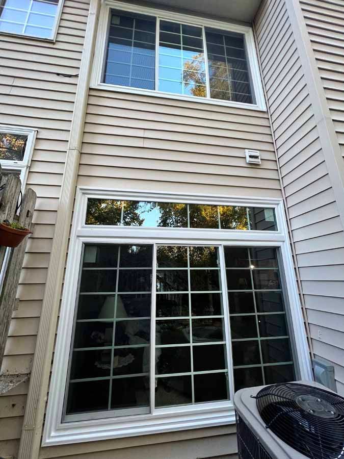 A large window on the side of a house next to an air conditioner.