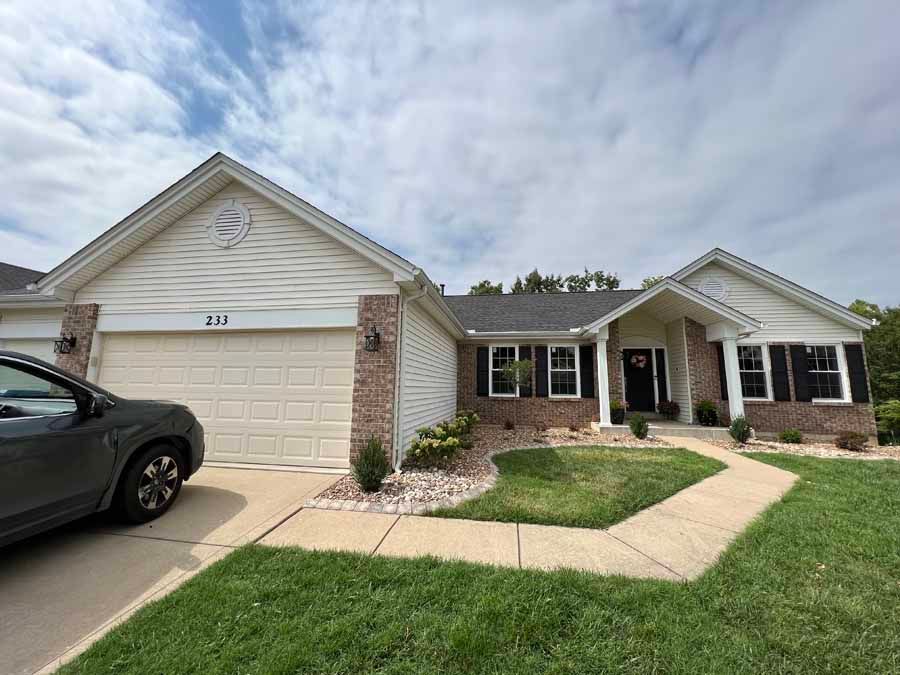 A car is parked in front of a large house.