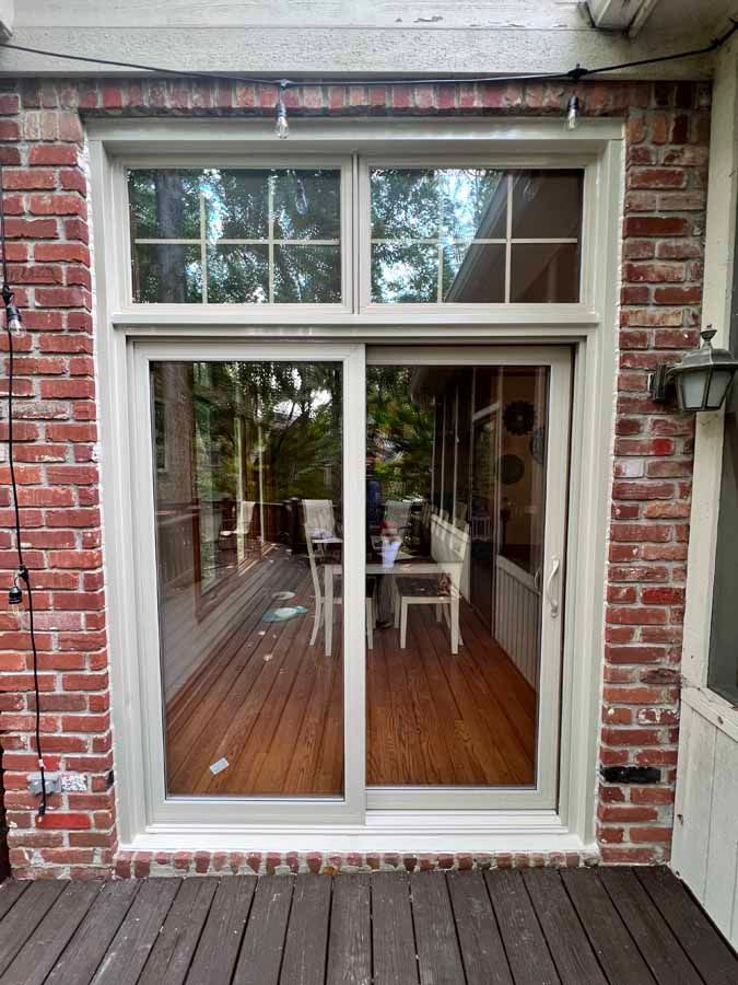 A sliding glass door with a brick wall and a wooden deck.