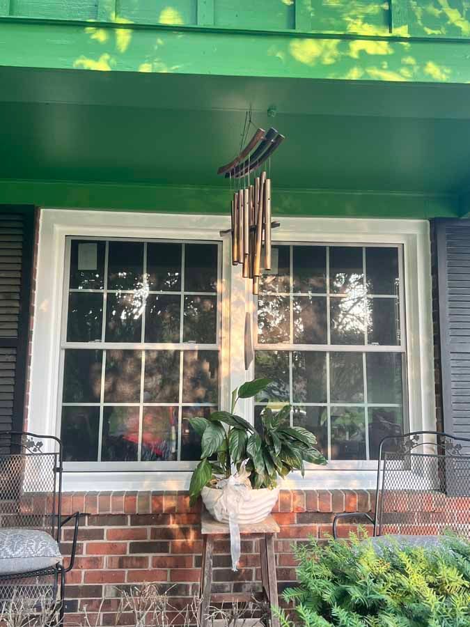 A wind chime is hanging from the roof of a house.