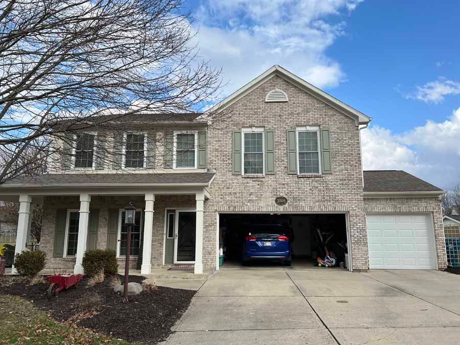 A large brick house with a car parked in the garage.