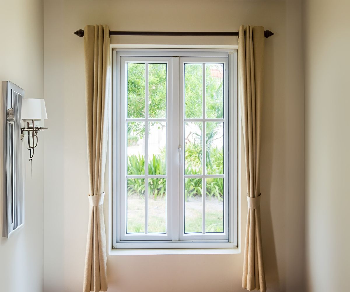 A bedroom with a large window and curtains.