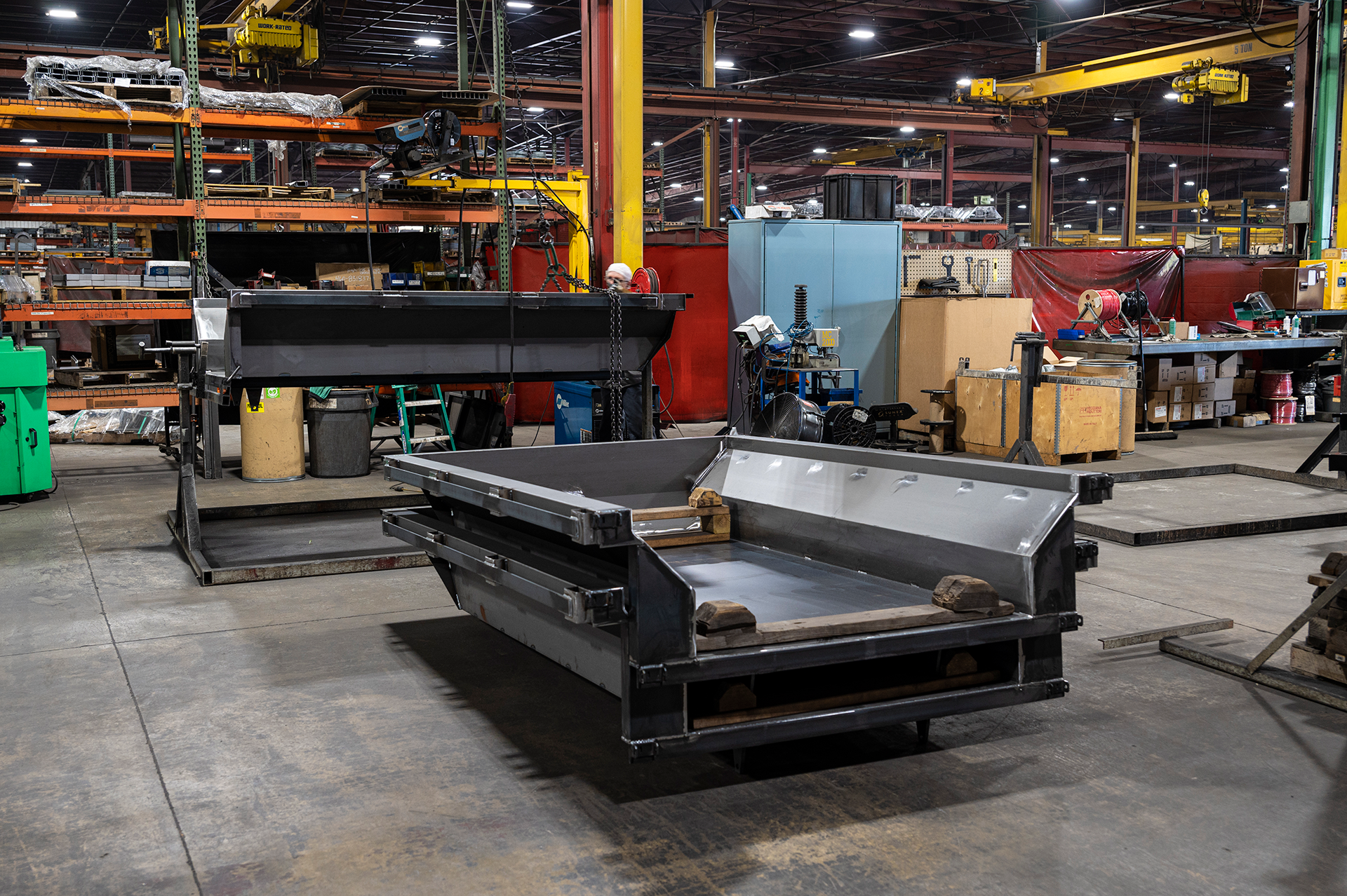 Two men examining trailers in an outdoor lot; one wearing a striped shirt and the other in a button-down shirt.