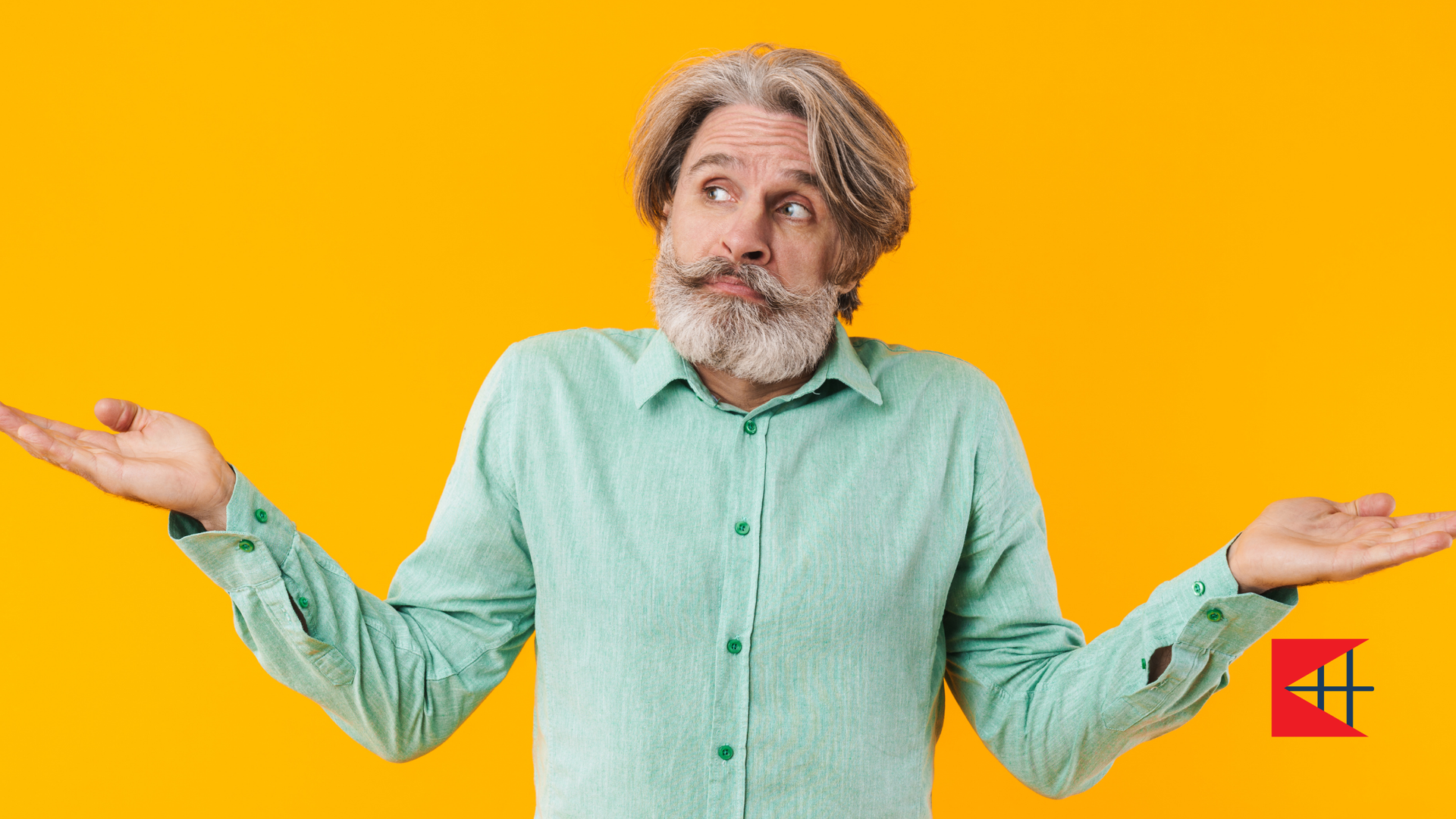 A man with a beard and a green shirt is shrugging his shoulders.