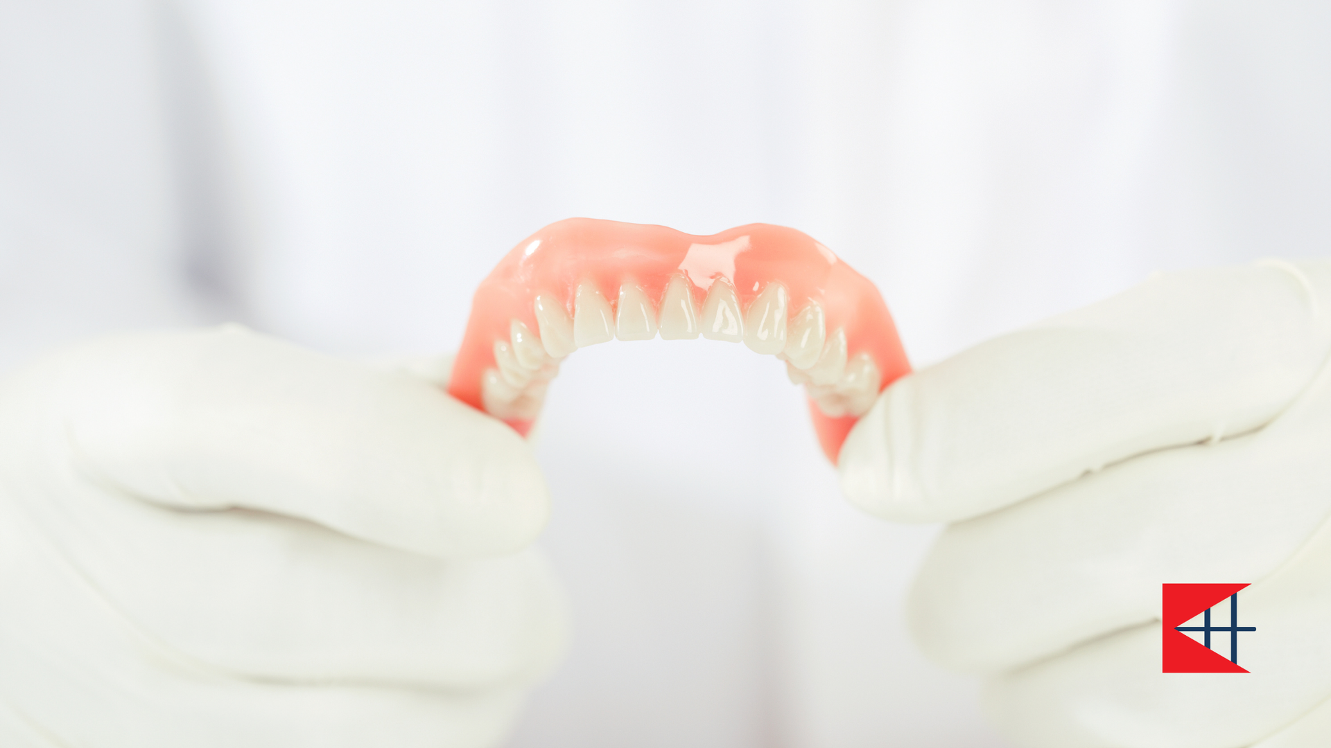 A person is holding a denture in their hands.