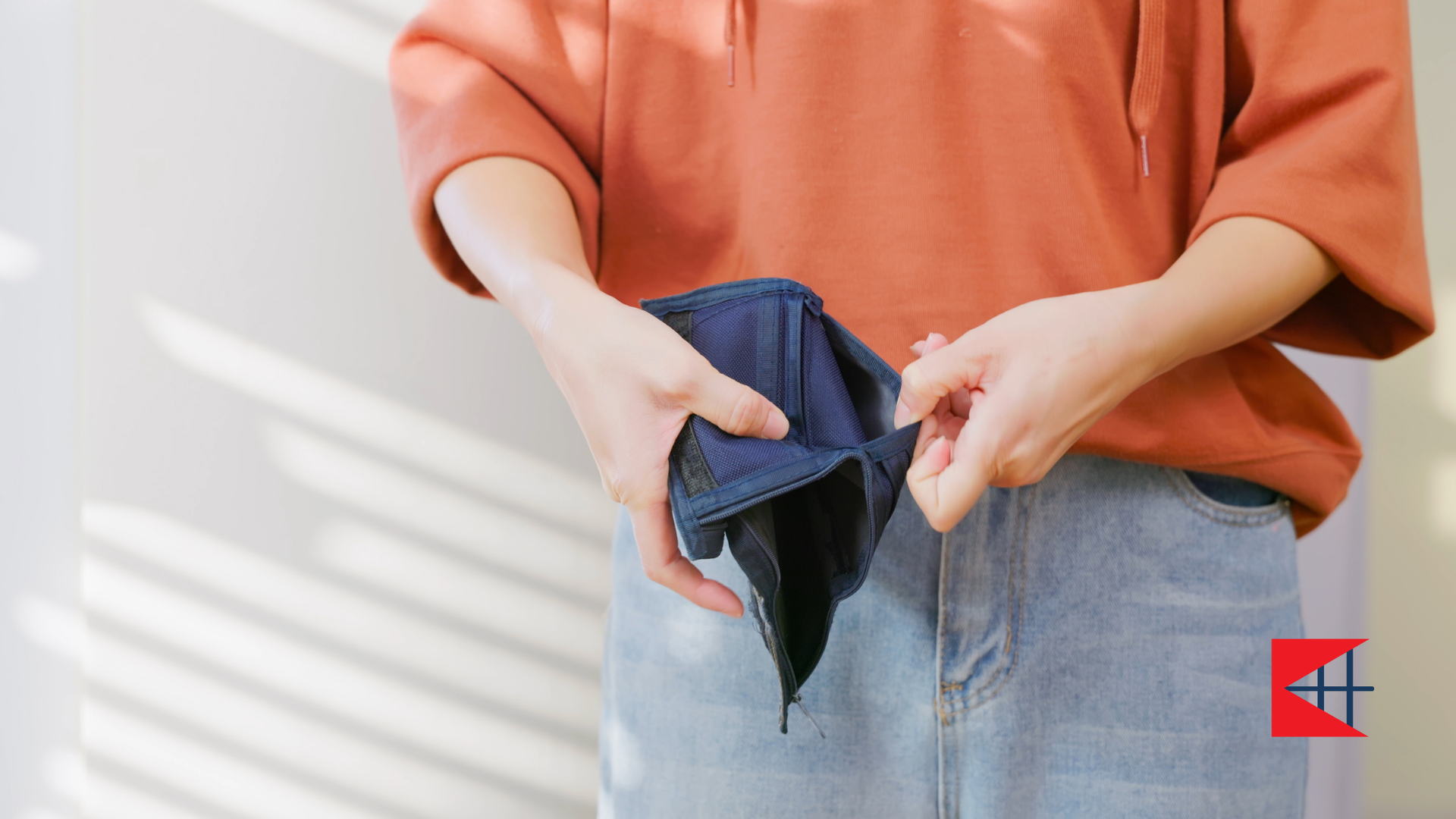 A woman is holding an empty wallet in her hands.