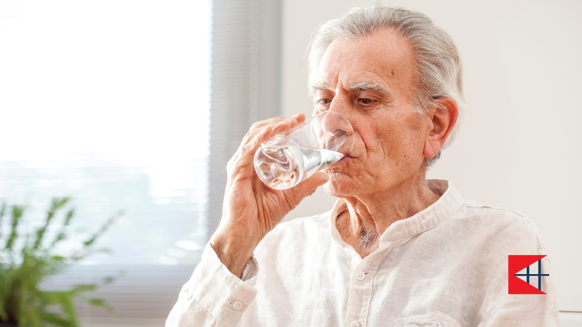 An elderly man is drinking water from a glass.