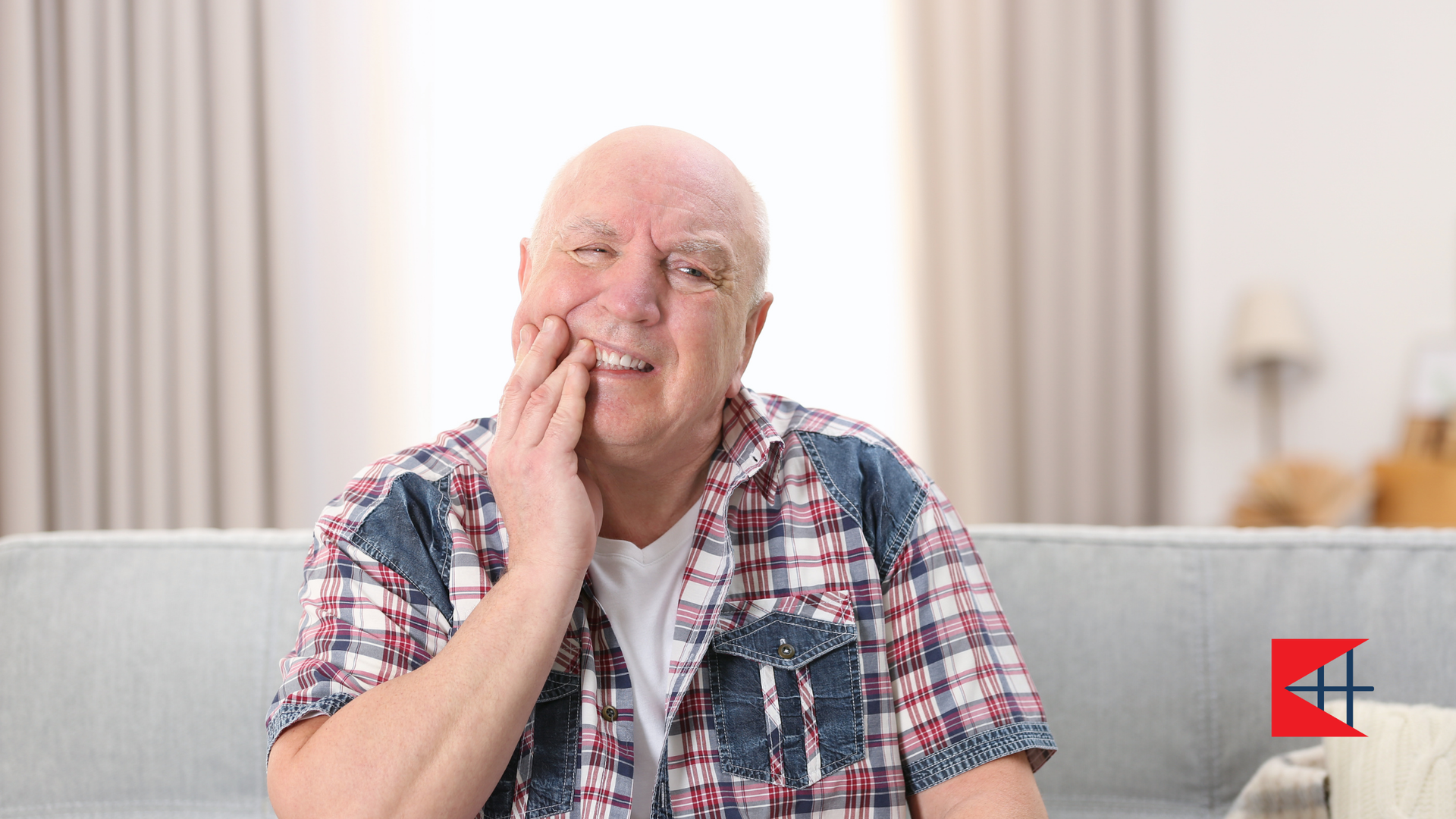 An elderly man is sitting on a couch with a toothache.