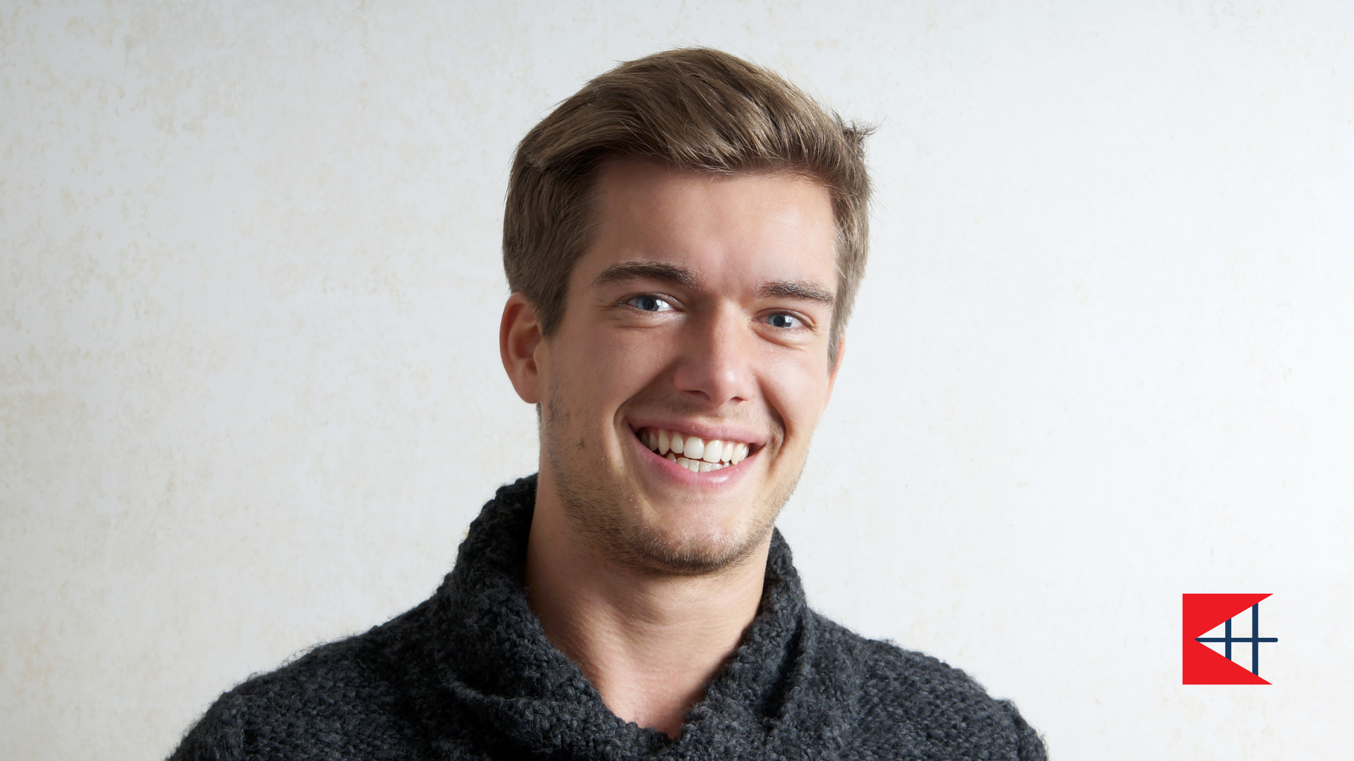 A young man in a sweater is smiling for the camera.