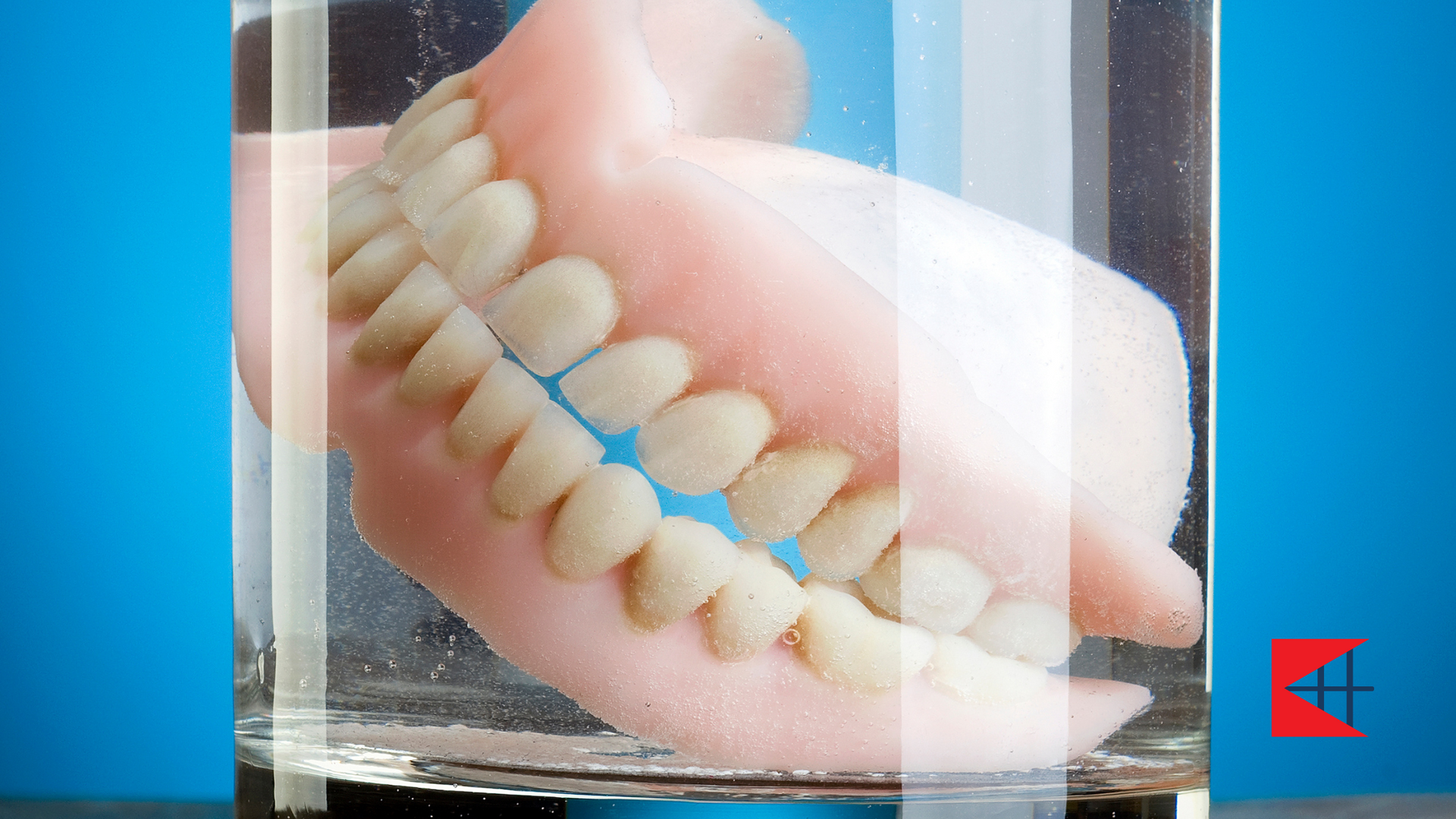 A denture is floating in a glass of water.