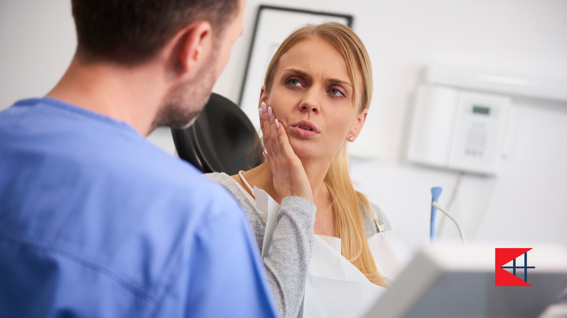 A woman is sitting in a dental chair talking to a dentist.