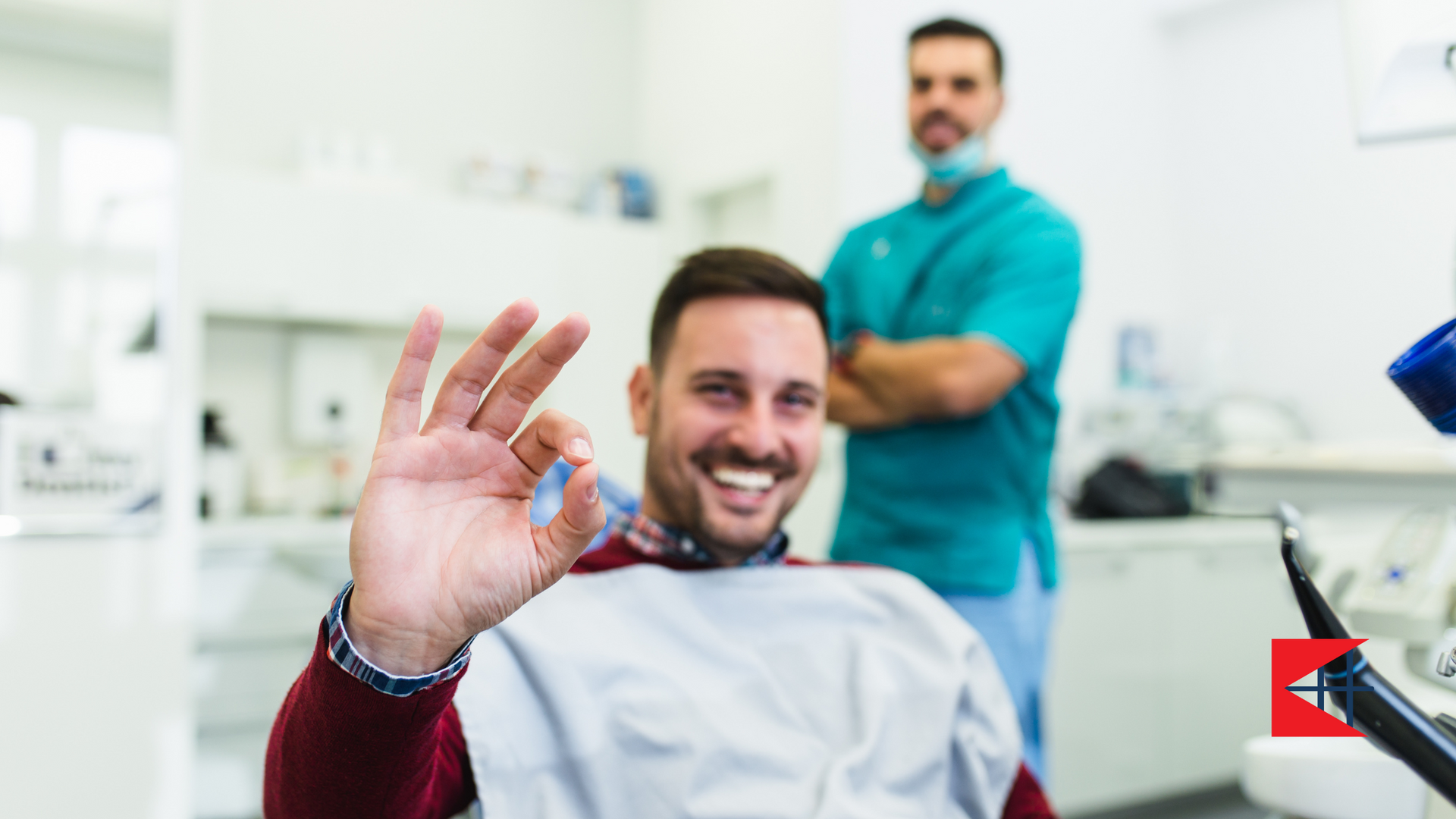 A man is sitting in a dental chair giving an okay sign.