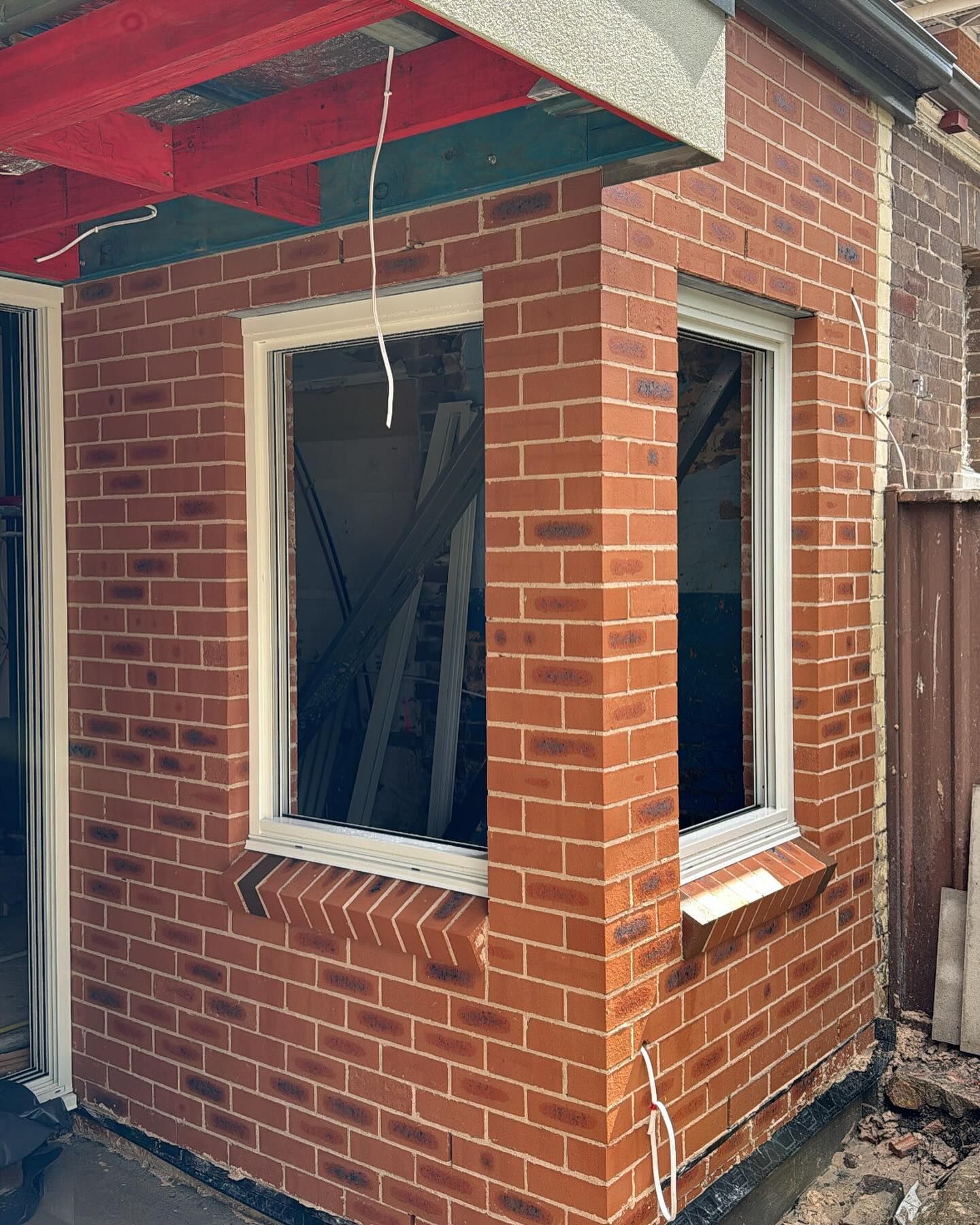 Brick building with open windows, under construction, red brick, white window frames.