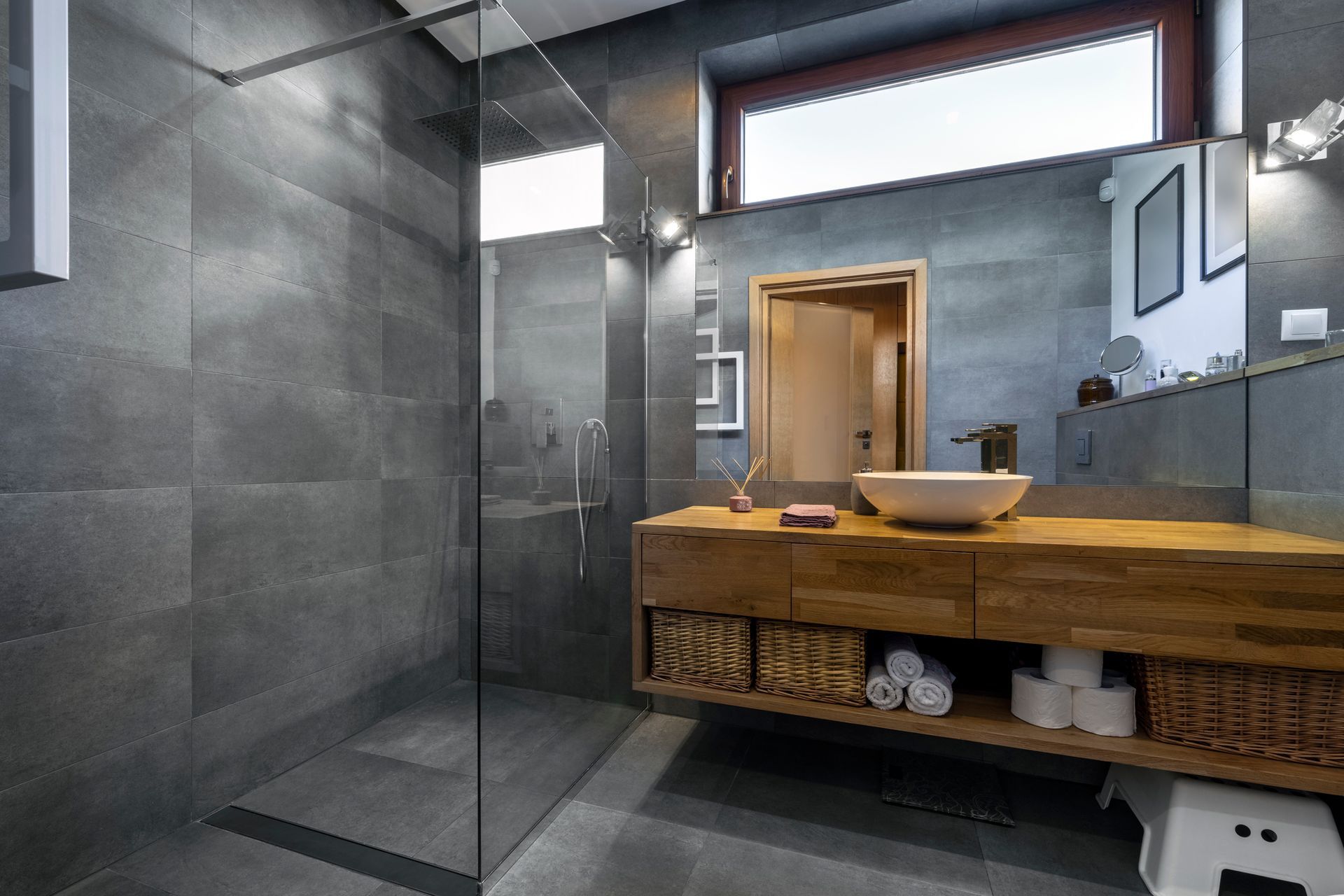 A bathroom with a walk in shower , sink , mirror and window.