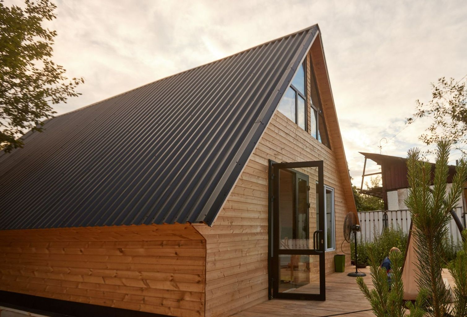 A small gray house with a porch and lawn chairs in front of it.