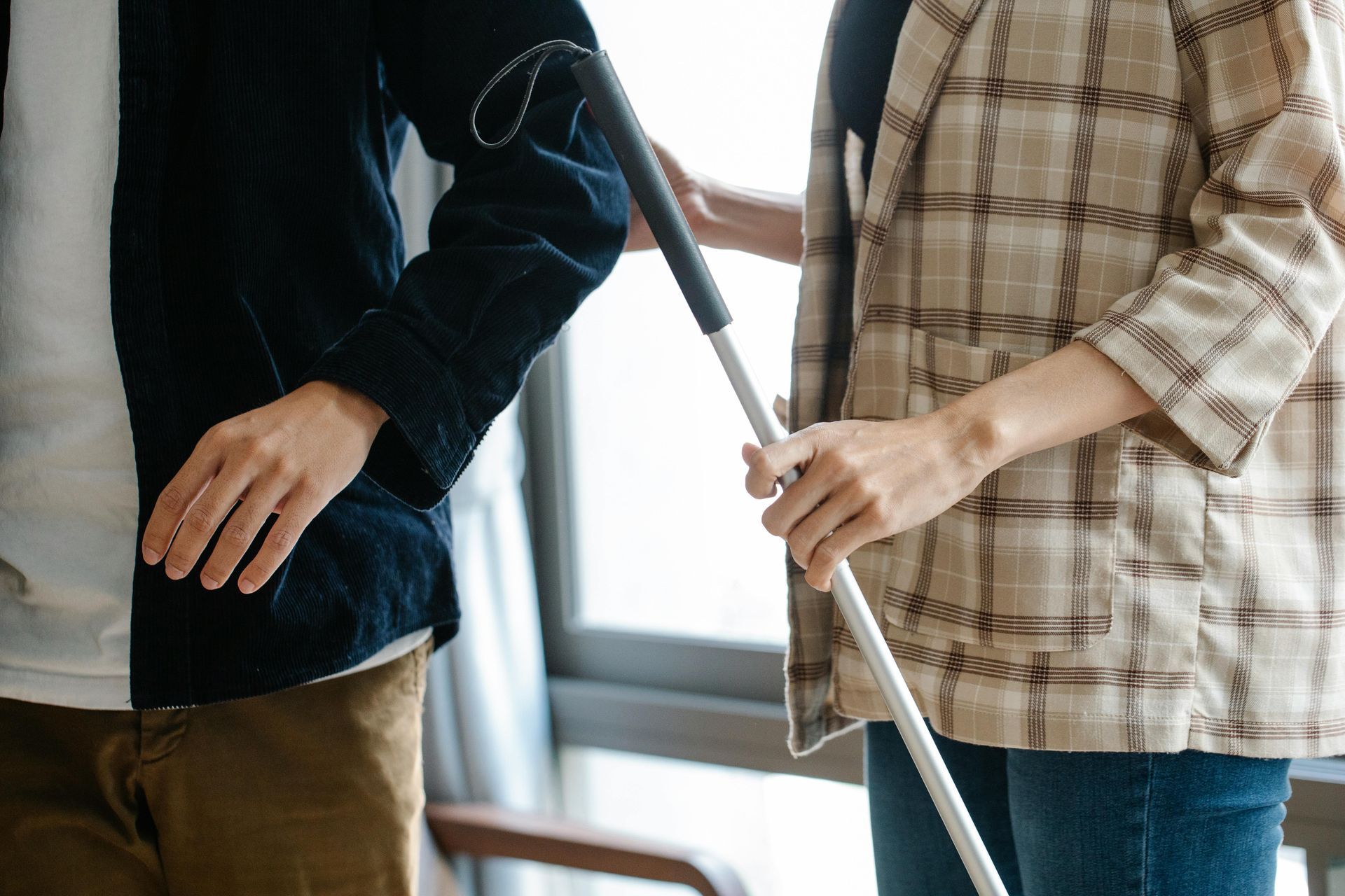 A man and a woman are standing next to each other holding a cane.