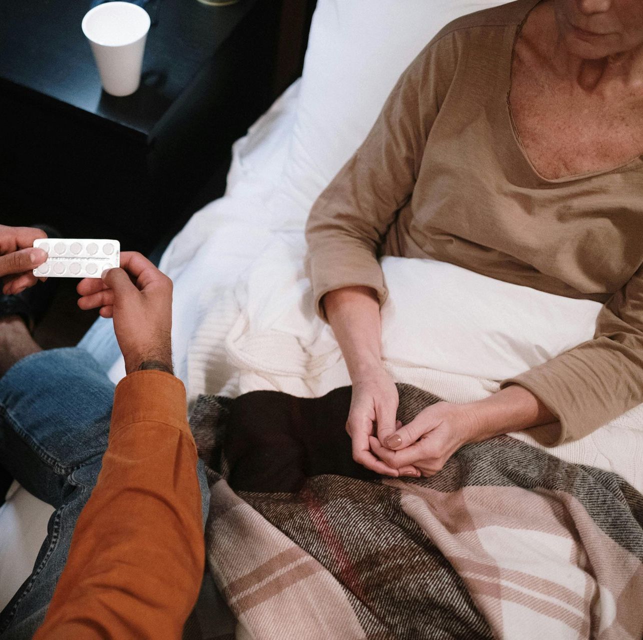 A man is giving a pill to a woman in a bed