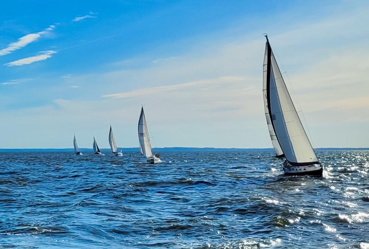 Boats sailing in a line formation on sunny afternoon