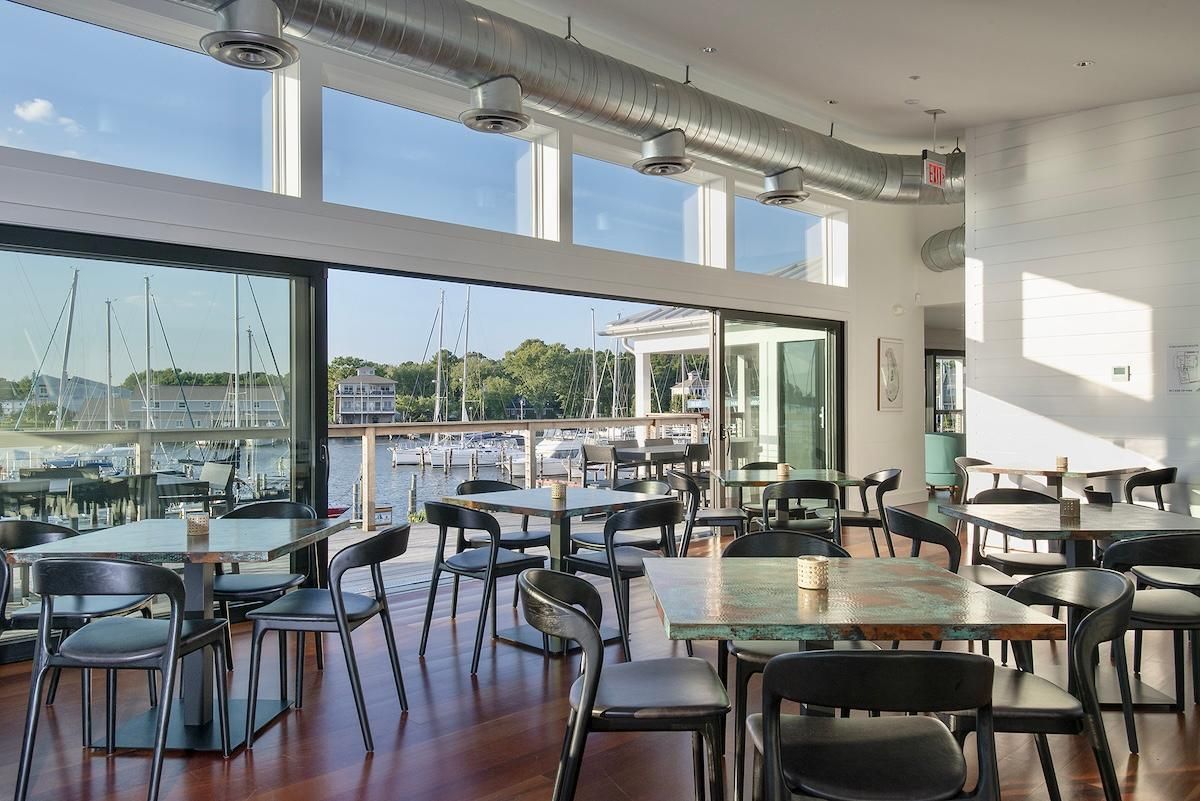 Restaurant dining room with large windows and glass doors overlooking the waterfront.