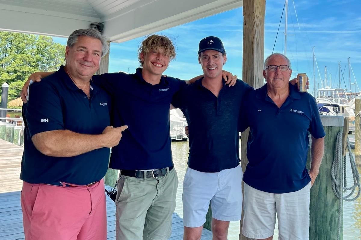 Outdoor group photo of marine technicians in front of large boat shop with its doors open