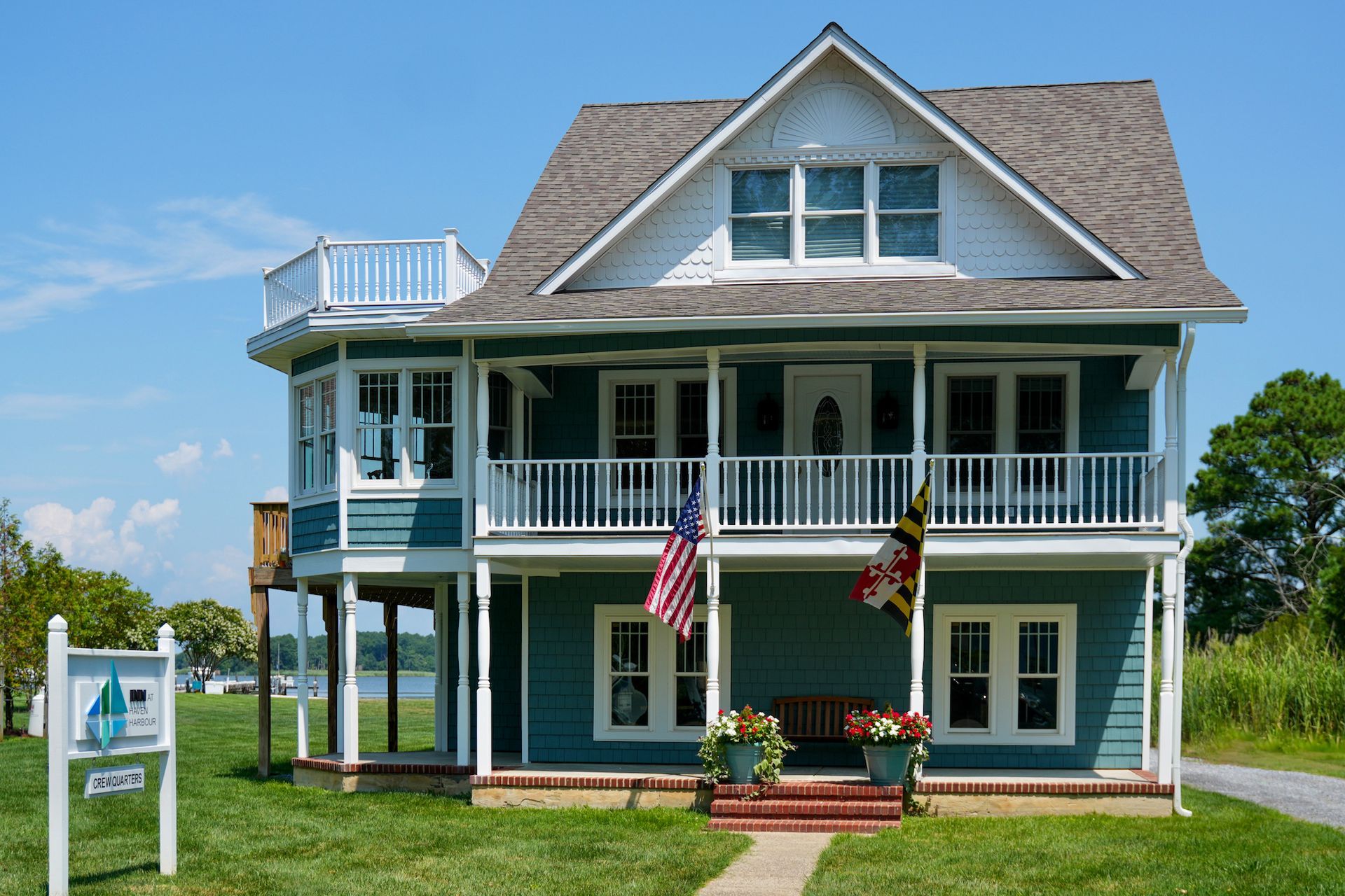 Street facade of three story home with double-decker porch and center gable, pictured on sunny day.