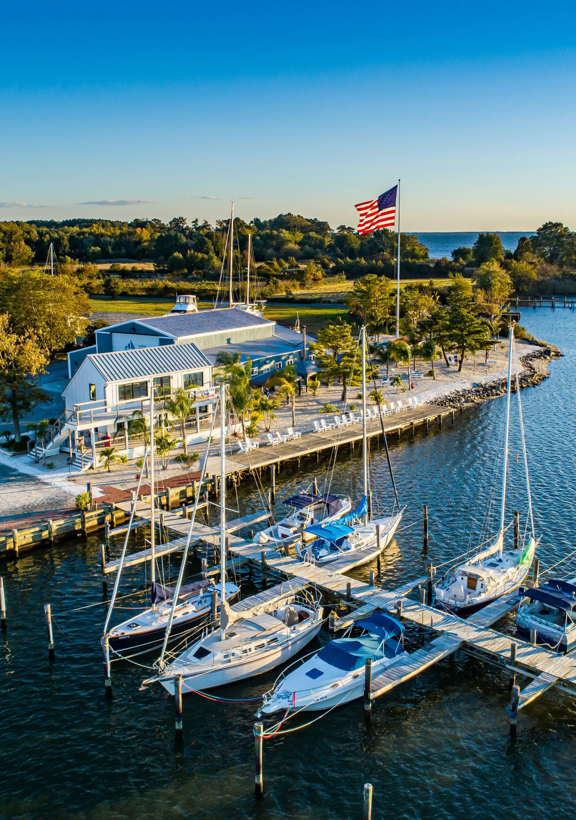 Sailboats, dock and beach with an American flag and blue sky in the background