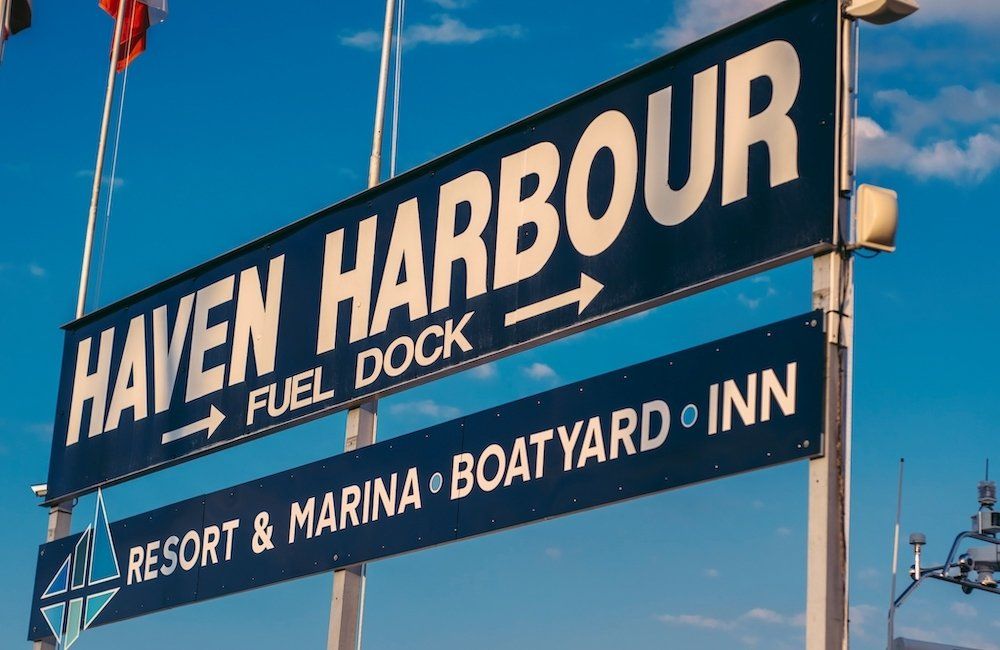 Large outdoor sign that reads Haven Harbour Fuel Dock with arrows