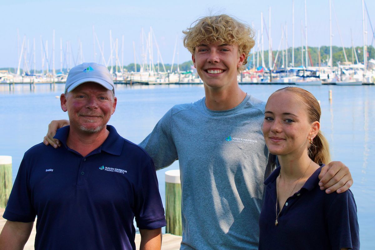 Group of employees pictured outside on a sunny summer day with boats in the background