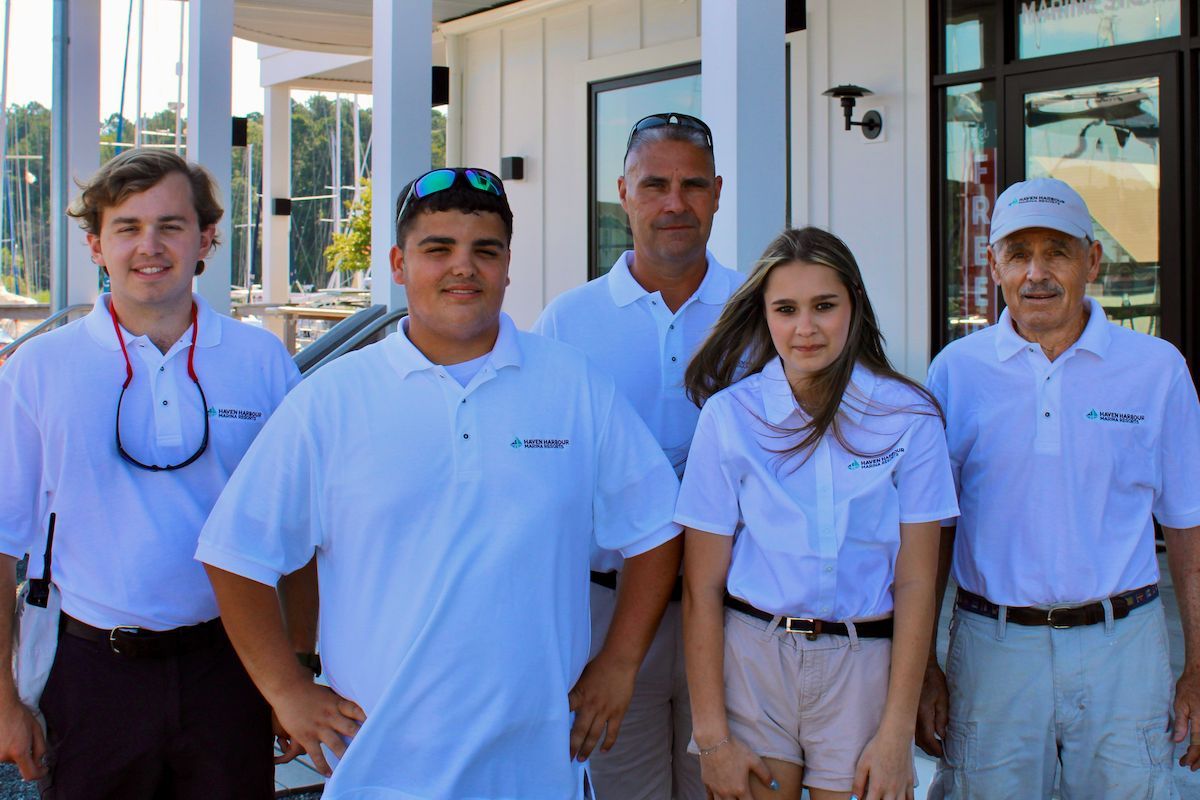 Group of employees pictured outside on a sunny summer day with boats in the background