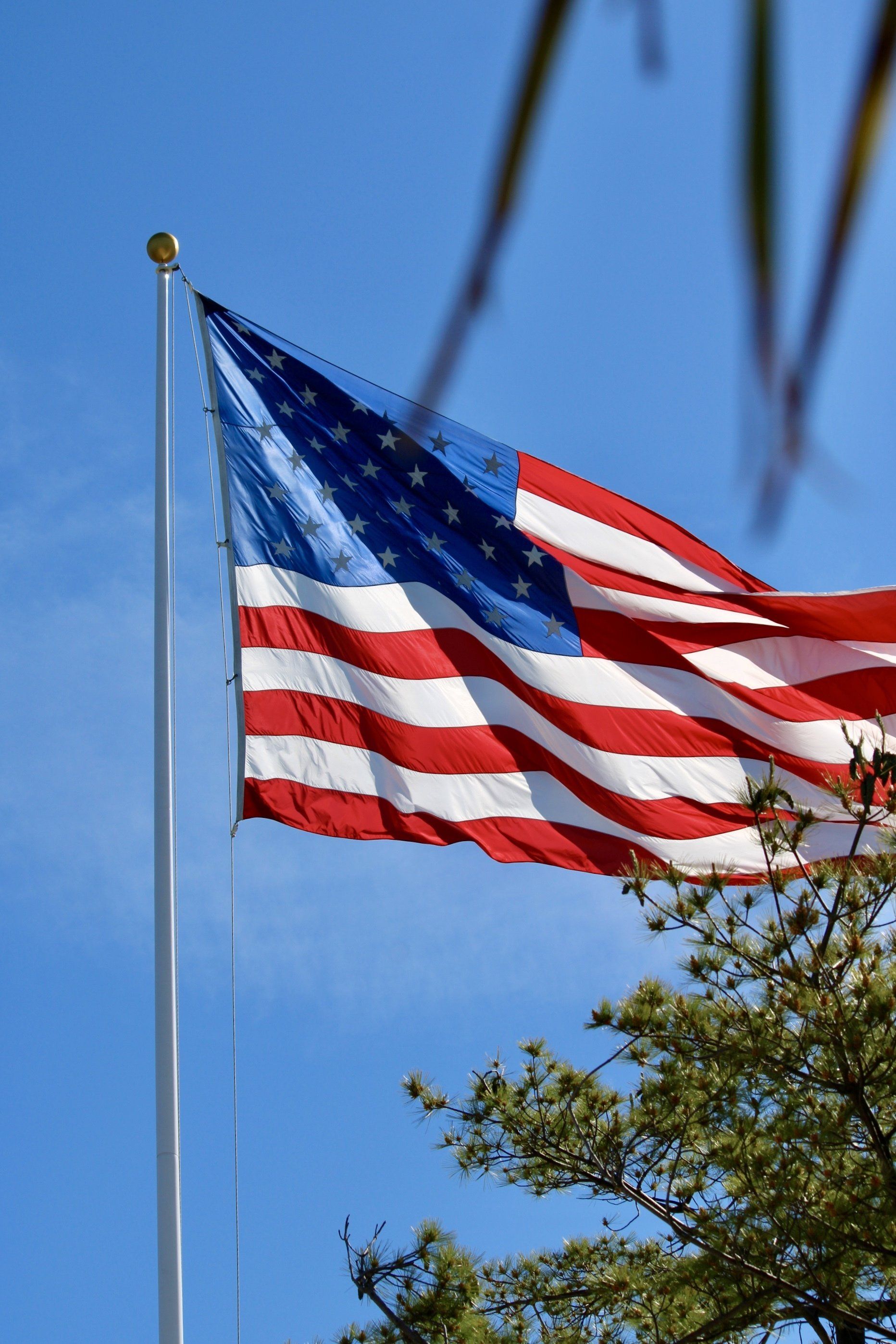 Large American flag flying outside against a blue sky