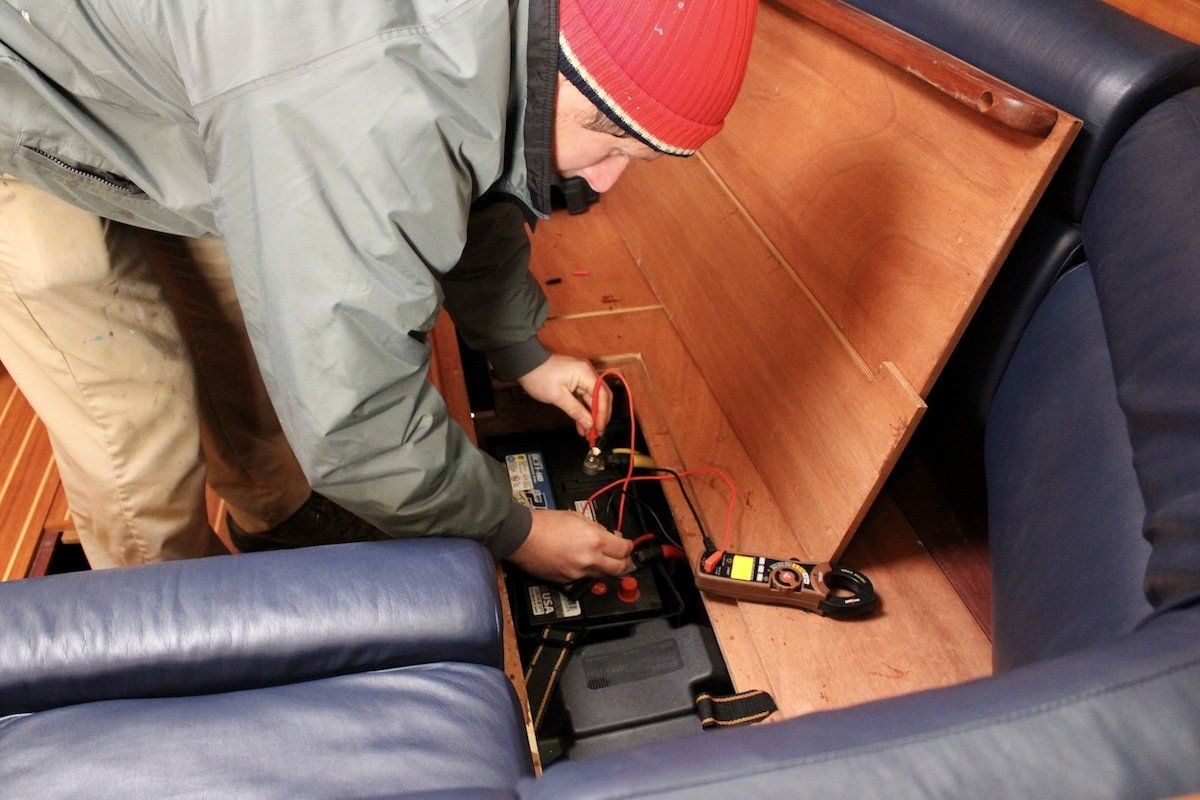 Service technician performs battery-bilge check service on-board sailboat