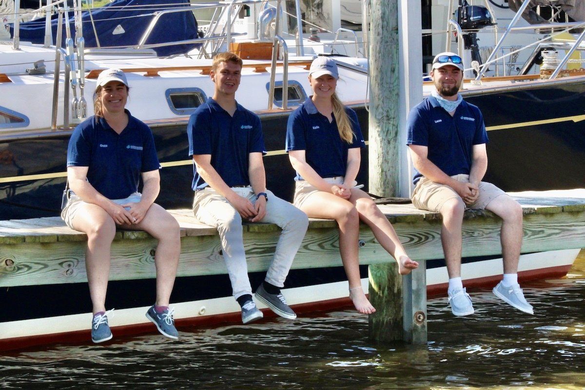 Group of employees pictured outside on a sunny summer day with boats in the background